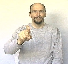 <p><span style="font-size: medium">starts as an index finger and changes into an "X" hand shape as it moves toward the person</span></p>