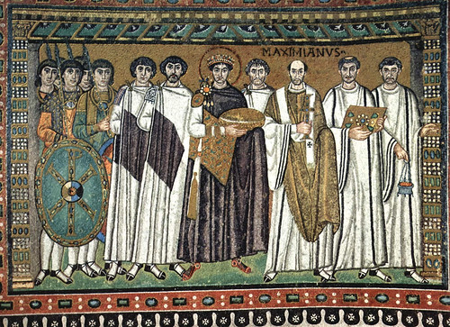<p>Bringing bread for mass, standing on Christ&apos;s RIGHT SIDE- hierarchy of place and scale. Flanked by military and clerical attendants. clerics closest to the apse. Justinian is with the clerics. the military is next to Jesus (protect him) Justinian has a halo, not a sign of holy just that he is a saint. (roman tradition). Bishop (labelled) standing closer to center. justinian has 12 attendants like Jesus 12 apostles. monogram of shield- Chi Ro, means Justinian rules in the name of christ. justinian has fancy shoes.within Heavenly Sphere</p>