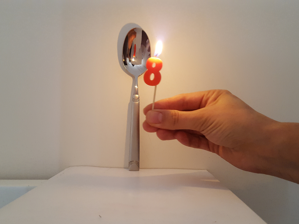 <p>The front surface of a spoon acts like a concave mirror, while the back side acts like a convex mirror.</p>