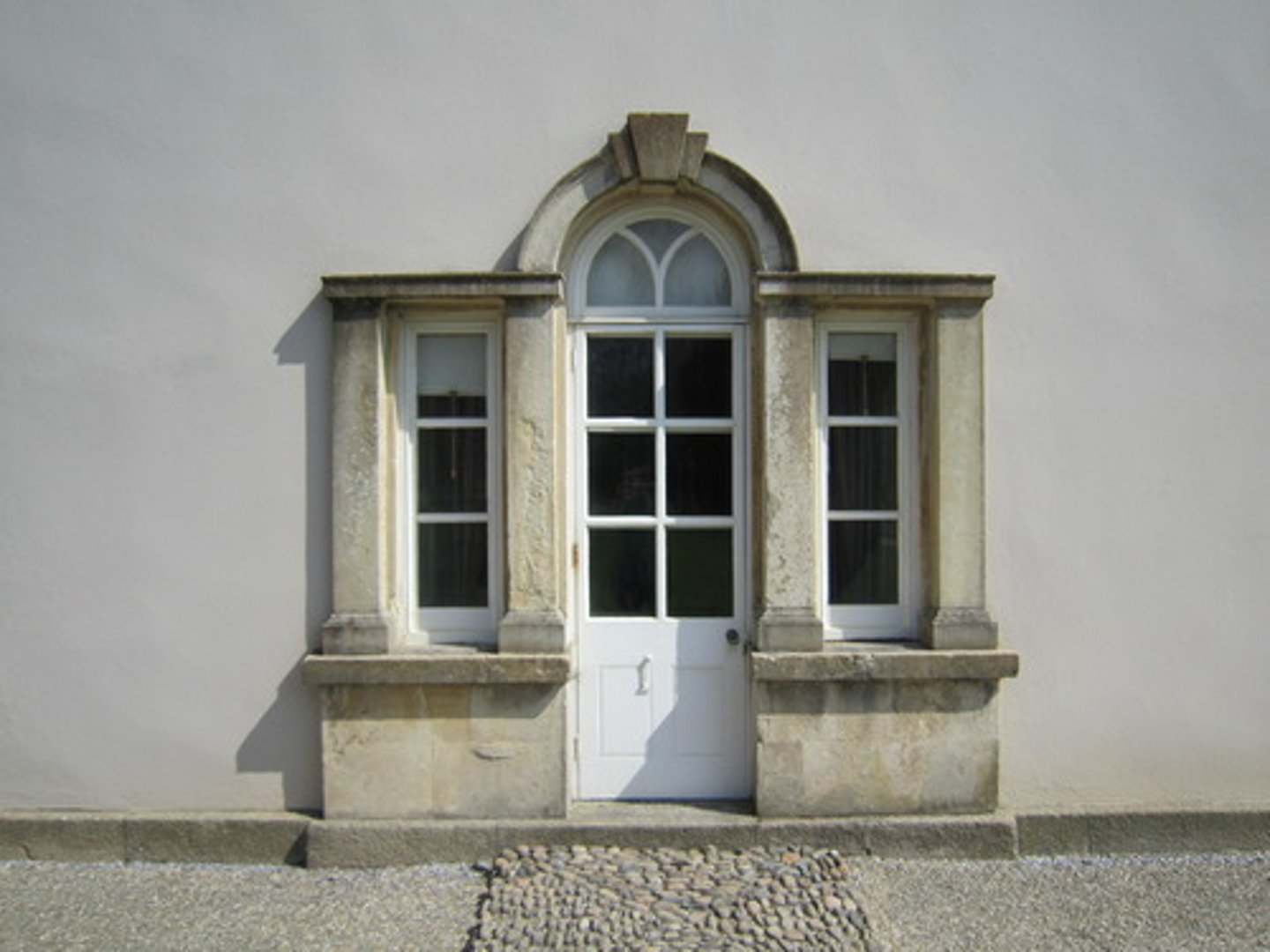 <p>A door opening with a semicircular window above and flanked by vertical windows</p>