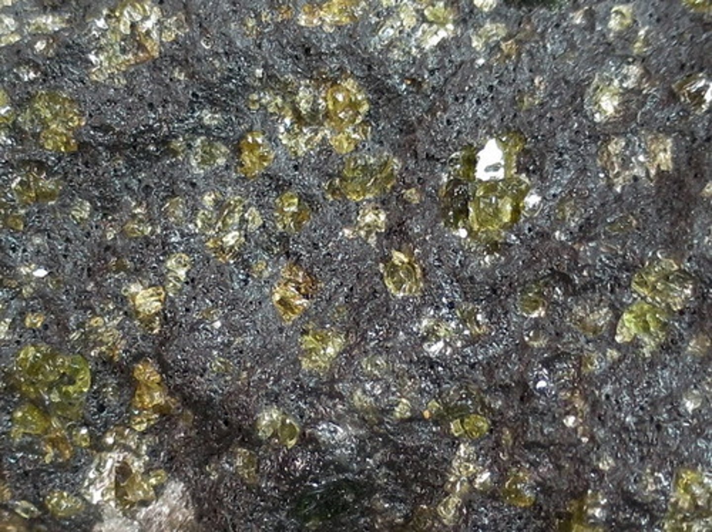 <p>This example has abundant olivine phenocrysts, with smaller amounts of white plagioclase. There are lots of small bubbles, but no big ones. (volcanic rock - quickly-cooled, fine-grained or glassy)</p>