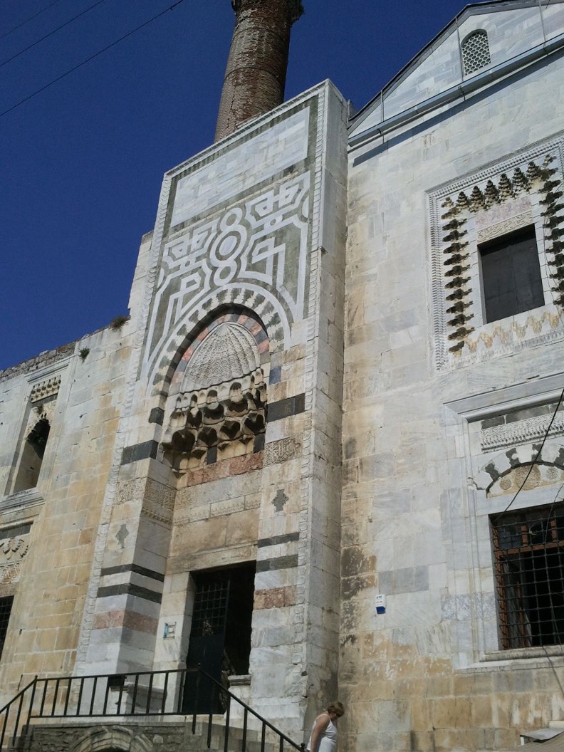 <ul><li><p>A different form of congregational mosque associated with the Beylik principalities</p><ul><li><p>Closer to the most ancient mosques (Great Mosque of Damascus), with a long, shallow, two-bay hall and courtyard, but the hall is intersected by two central domes</p></li></ul></li><li><p>The pishtaq is now 3-D, forming an <strong>Entrance Block</strong>, and decorated with an inlayed stone interlace pattern based on Seljuk designs</p><ul><li><p>Multi-media: different colored marbles, low relief arabesques, and muqarnas</p></li><li><p>Actually very little carved ornamentation</p></li><li><p>Sculptor used muqarnas to create a window frame, wrapping them around the window opening</p></li></ul></li><li><p>The interior is extremely stark and plain but contains spolia from the ruins of the great Hellenistic city of Ephesus nearby</p></li><li><p class="MsoListParagraphCxSpLast">The mihrab is also simple and stark, with black marble inserts in an interlace pattern that complements the entrance</p></li></ul><p></p>