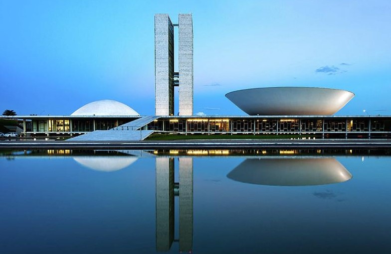 <p>It’s similar to the UN HQ. Pictured in the tall, overarching buildings is the <strong>House of Representatives and the Senate</strong>, with the smaller building in the back being the <strong>Dept. of Justice</strong>. Important things to mention are <strong>the hierarchy</strong> (Congress towers over the DOJ, but the DOJ is always there in the back), and the <strong>modern nature</strong> of the structure (representing a move towards a modernist future).</p>