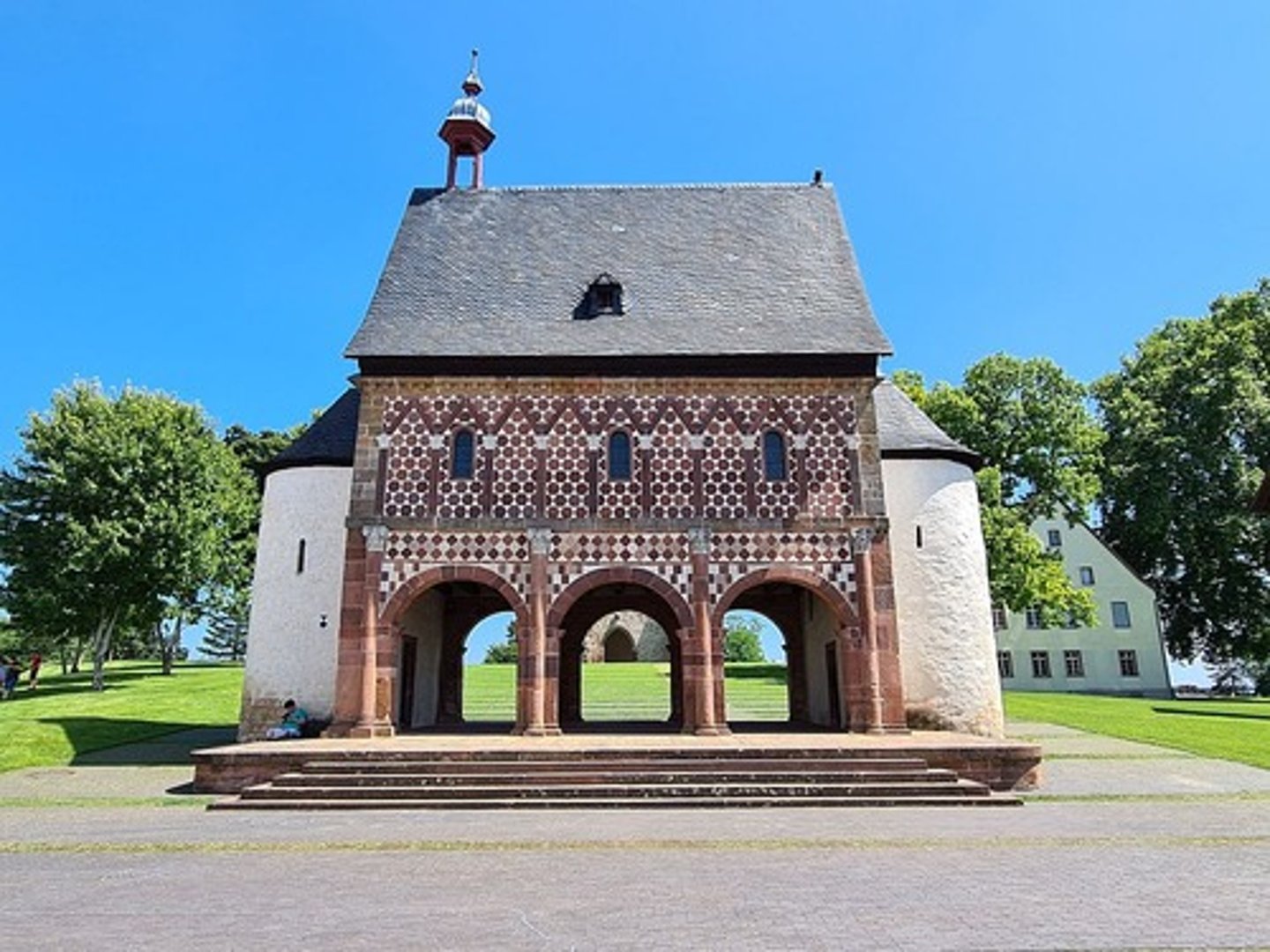 <ul><li><p><span style="background-color: transparent;"><span>Built at gatehouse of imperial monastery, foundation of Lorsch Abbey</span></span></p></li><li><p><span style="background-color: transparent;"><span>Charlemagne visited and elevated it to an imperial monastery</span></span></p></li><li><p><span style="background-color: transparent;"><span>He tied it into his program of church reform and education</span></span></p></li><li><p><span style="background-color: transparent;"><span>The torhalle constructed as monumental entrance to Lorsch Abbey, symbolizing imperial authority</span></span></p></li><li><p><span style="background-color: transparent;"><span>The design inspired by romanesque architecture (arches, pilasters, friezes)</span></span></p></li><li><p><span style="background-color: transparent;"><span>An example of the Carolingian synthesis of Roman heritage and Christian imperial ideology</span></span></p></li><li><p><span style="background-color: transparent;"><span>Resembles a Triumphal Arch(like Arch of Constantine)</span></span></p></li></ul><p></p>