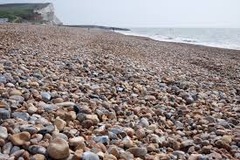 <p>Created by high energy waves and are steep + narrow - sand particles are washed away but larger shingle is left behind; single particles build up to create a steep slope.</p>