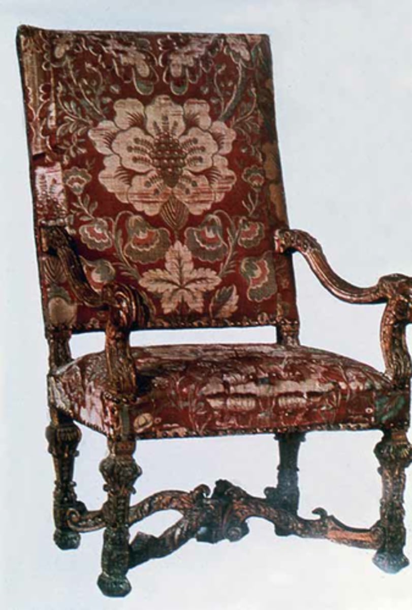 <p>The furniture from the reign of France's Louis XIV—the ruler who oversaw the construction of Versailles—is characterized by intricate carving, rare wood, and heavy upholstery, like in this walnut seat with a dark, brocade fabric. Telltale signs of Louis XIV-style chairs include straight backs, curved armrests, and crossed stretchers, which can either be H-or X-shaped (as on this chair).</p>