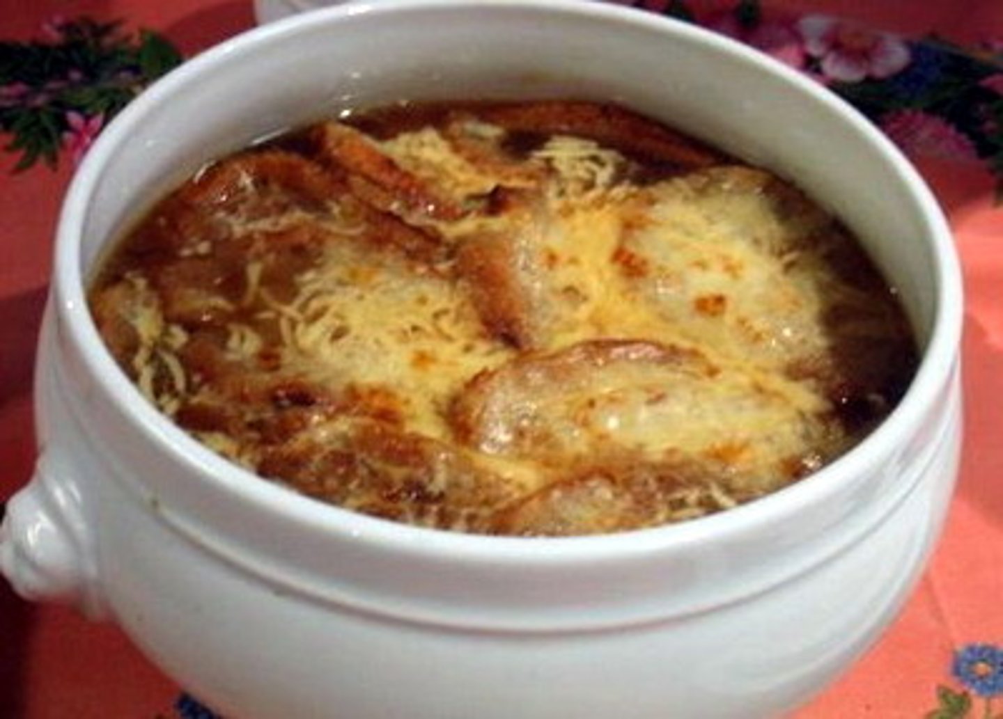 <p>onion soup with melted cheese on top</p>