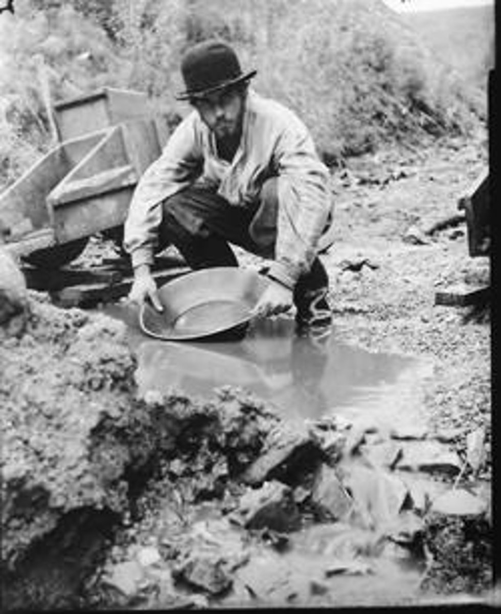 <p>Searching for gold by collecting, then washing gold-bearing gravel in a pan</p>