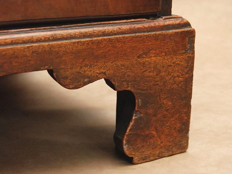 <p>Support for case furniture consisting of two brackets mitered and joined below the corners of the piece's body</p>