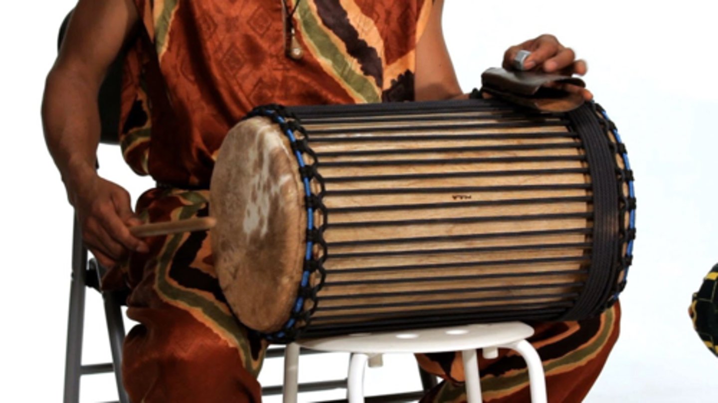<p>double-headed, played with a stick, worn on the shoulder using a strap, played with a bell-like instrument mounted on it</p>