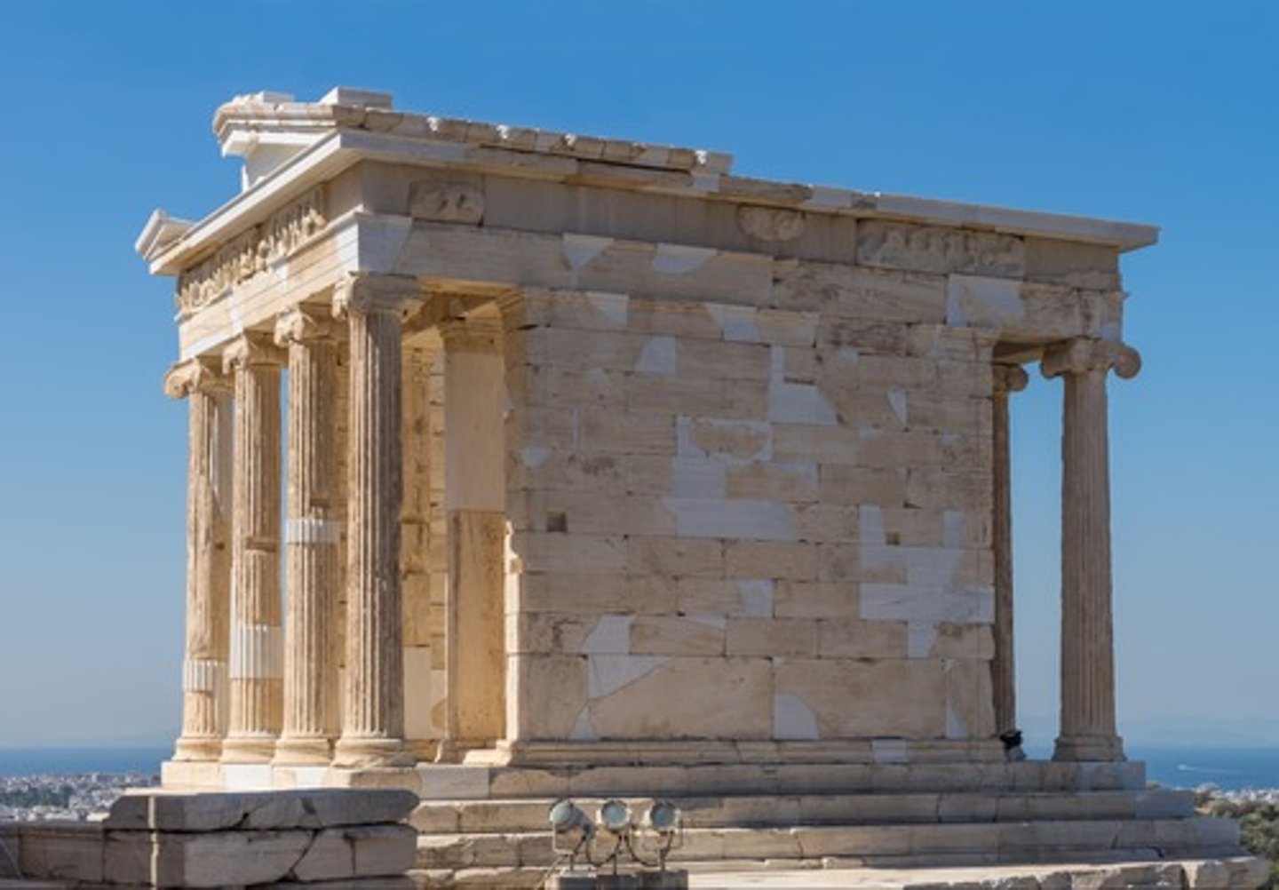 <p>ionic order, first fully ionic at Acropolis, columns on front and back, none on side. nike adjusting her sandal inside, commoners perform rituals at fron tof temple and glimpse nike, after temple create parapet to prevent falls</p>