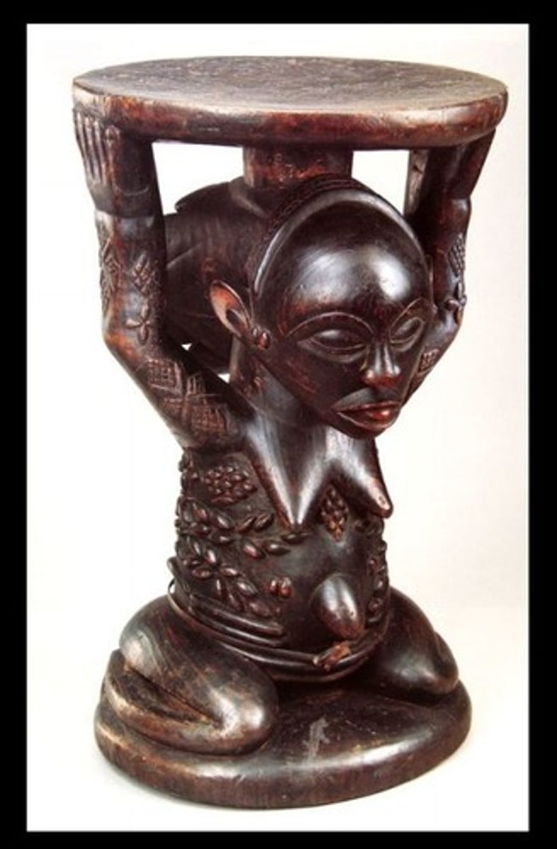 <p>Seat for the king</p><p>(Female figure with weight bearing on them)</p><p>Kings spirit is reborn in a woman and this figure represents that woman</p><p>Very powerful, may be kept in other villages to protect the king from spiritual damage</p><p>The life of the king is in the hands of women that surround him</p>