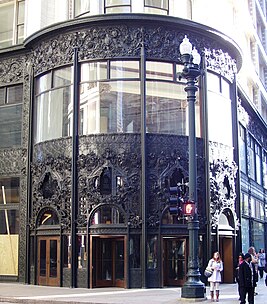 <p>Another creation by Louis Sullivan in Chicago, characterized by a richly decorated entrance, floral motives, and a division between the ground floor, mezzanine, and upper floors with unique ornamentation placements.</p>