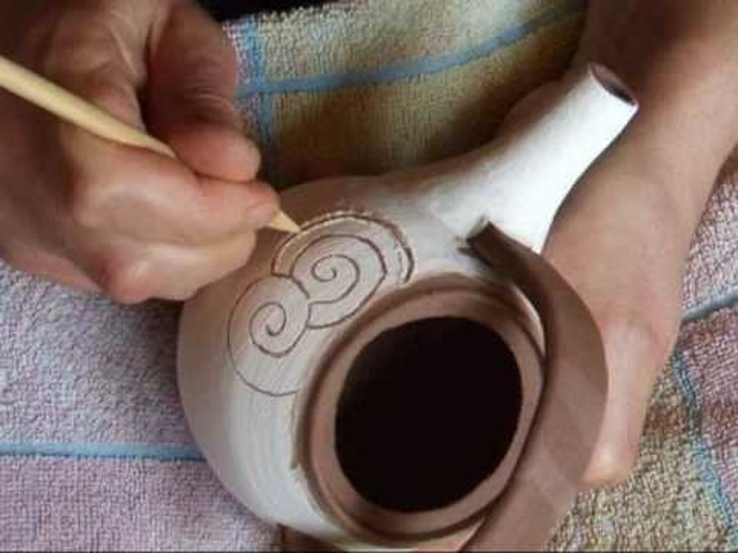 <p>The term comes from the Italian graffiare which means to scratch. Designs are drawn with a pointed tool that scratches through the slip to reveal the body.</p>