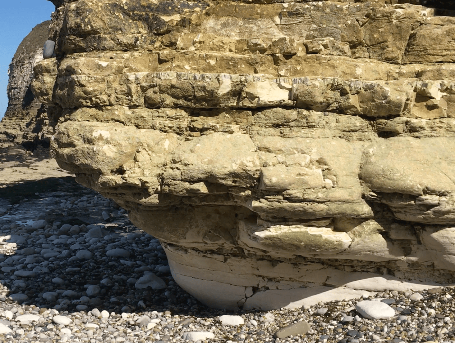 A curved indentation of about 1-2 m high extending along the base of a cliff