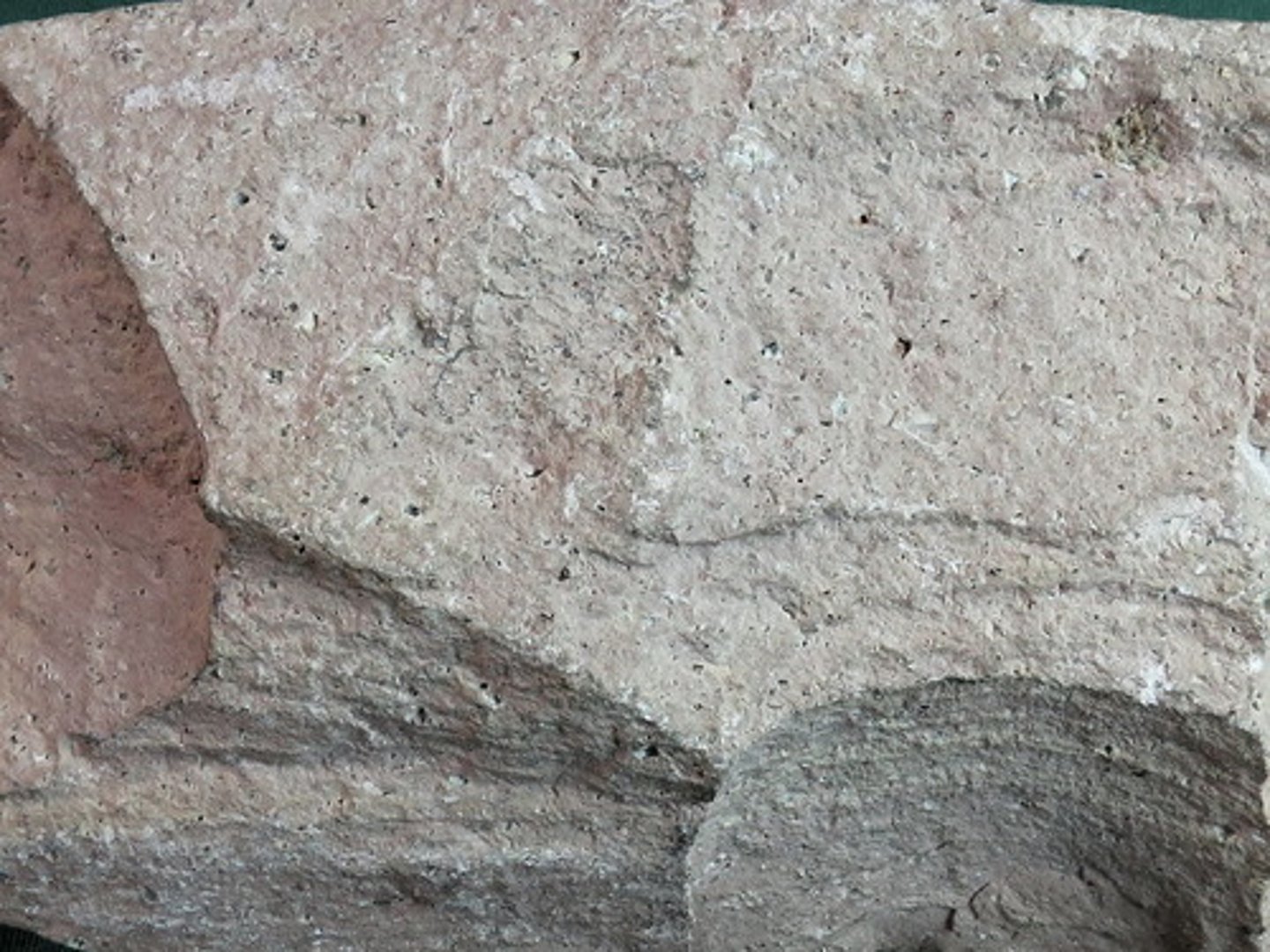 <p>This light-pink rock is rich in silica, with lots of quartz and feldspars. Most crystals are too small to see, but the light color indicates that the rock is rich in felsic minerals. There are some little gas bubbles, but few phenocrysts (volcanic rock -quickly-cooled, fine-grained or glassy)</p>