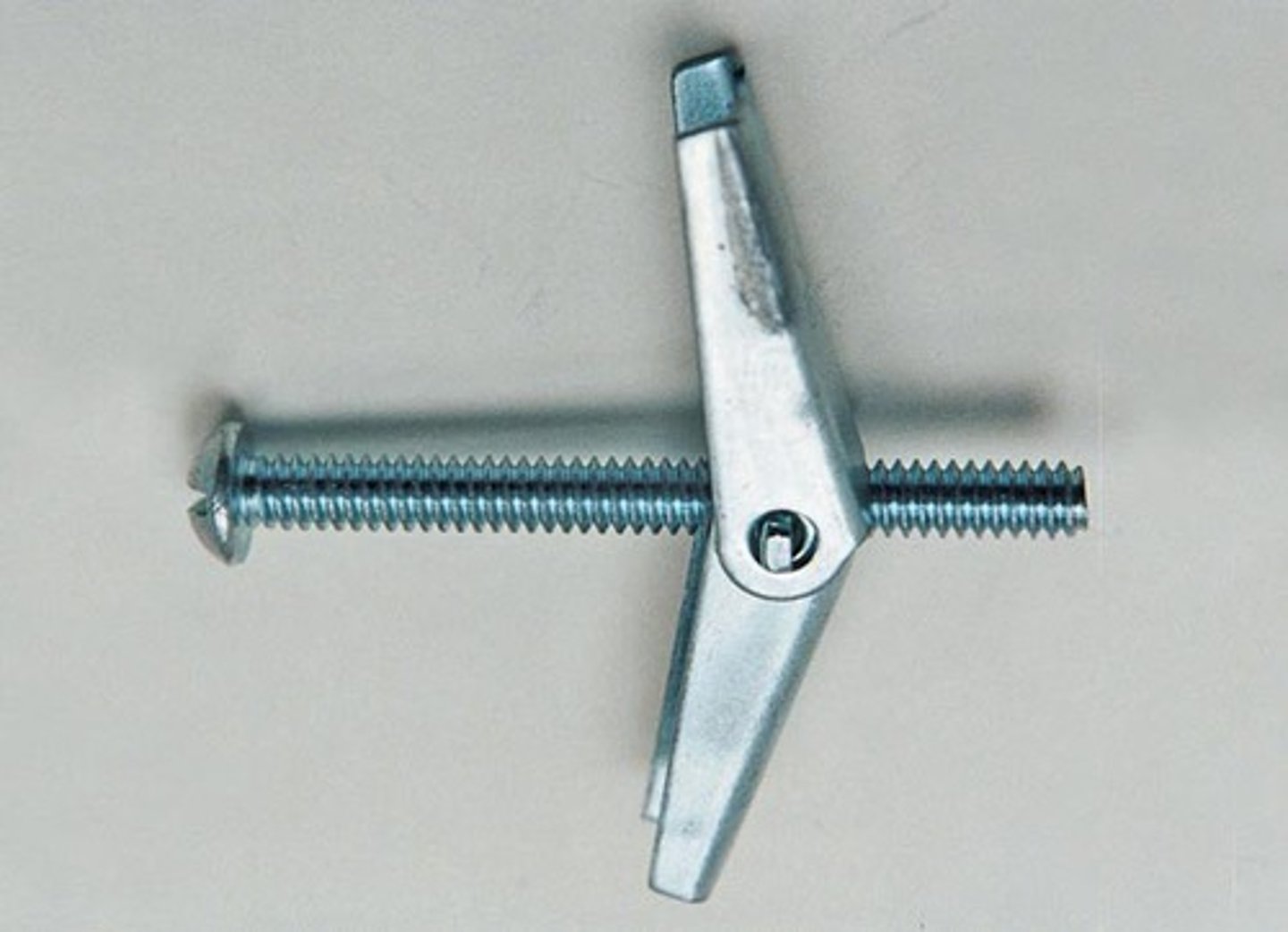 <p>An anchor bolt having two hinged wings that close against a spring when passing through a predrilled hole and open as they emerge to the inner surface of a hollow wall.</p>